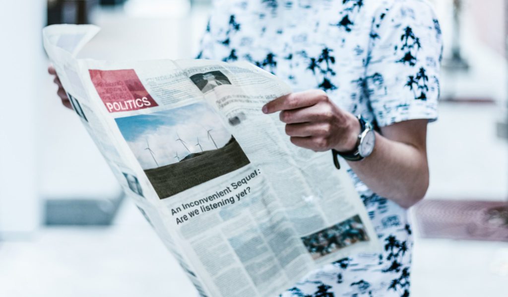 Man holding an open newspaper and reading the inside