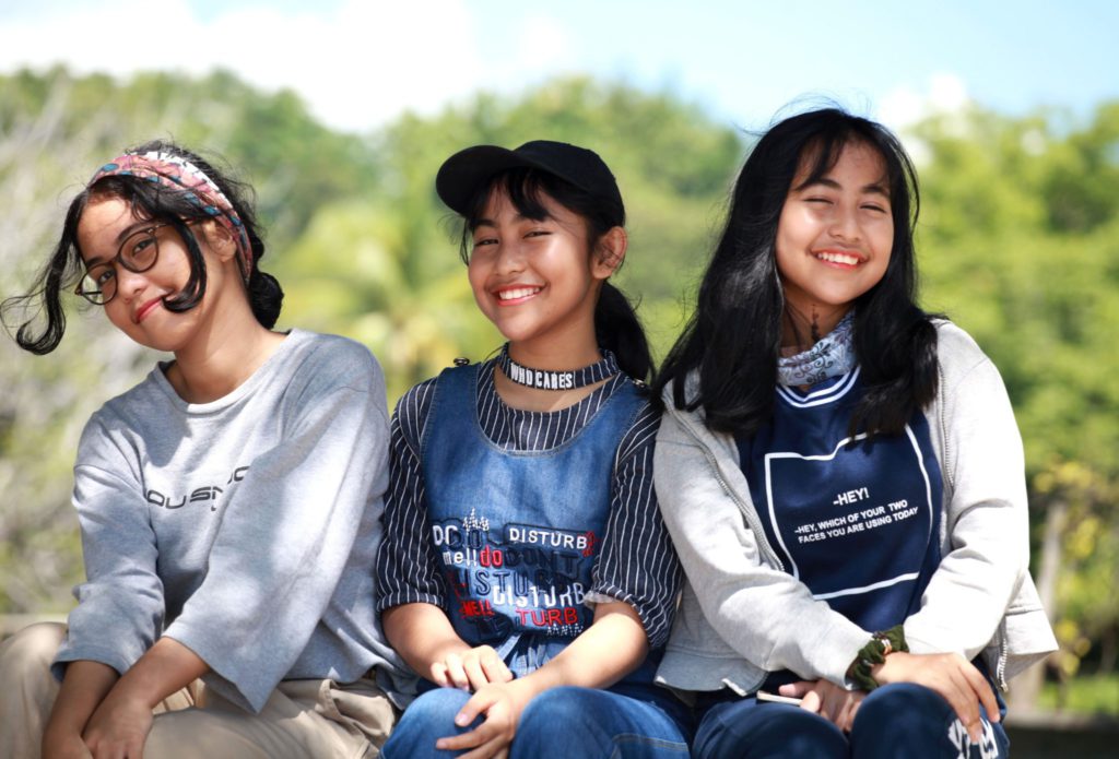 three tween girls sit together smiling